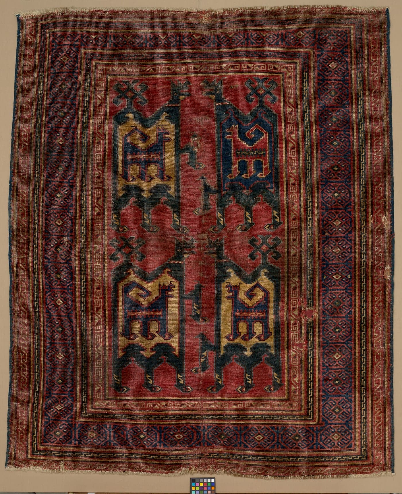 An early Anatolian rug with a yellow ground, showing two stylised animals facing each other, drawn entirely in straight lines and stepped diagonals.