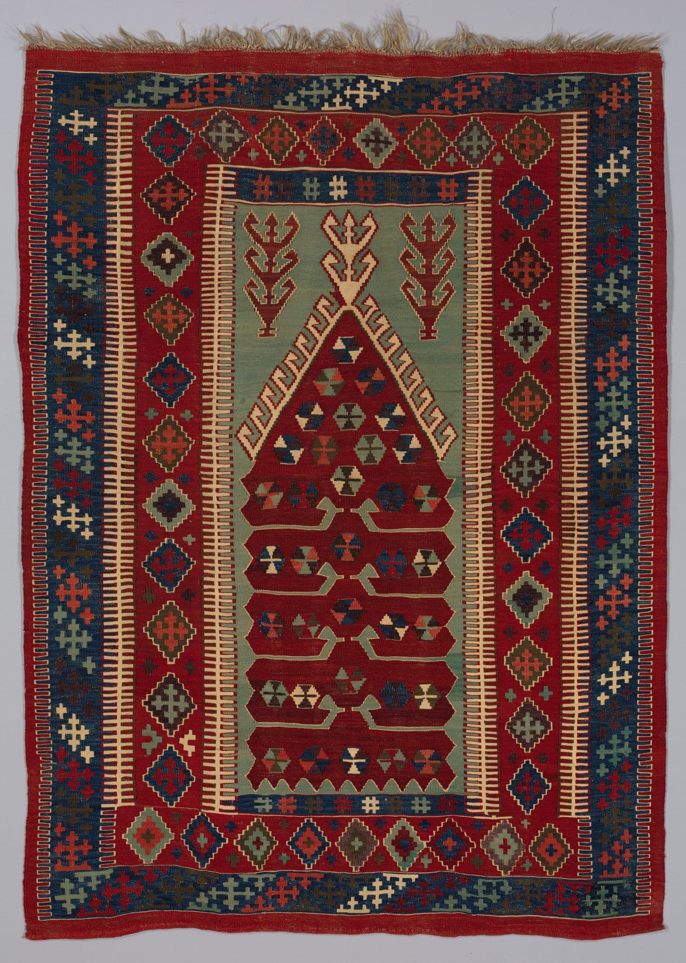 An Anatolian flatweave with large stepped medallions in red, blue and cream, every colour boundary running as a diagonal or a step rather than a vertical line.