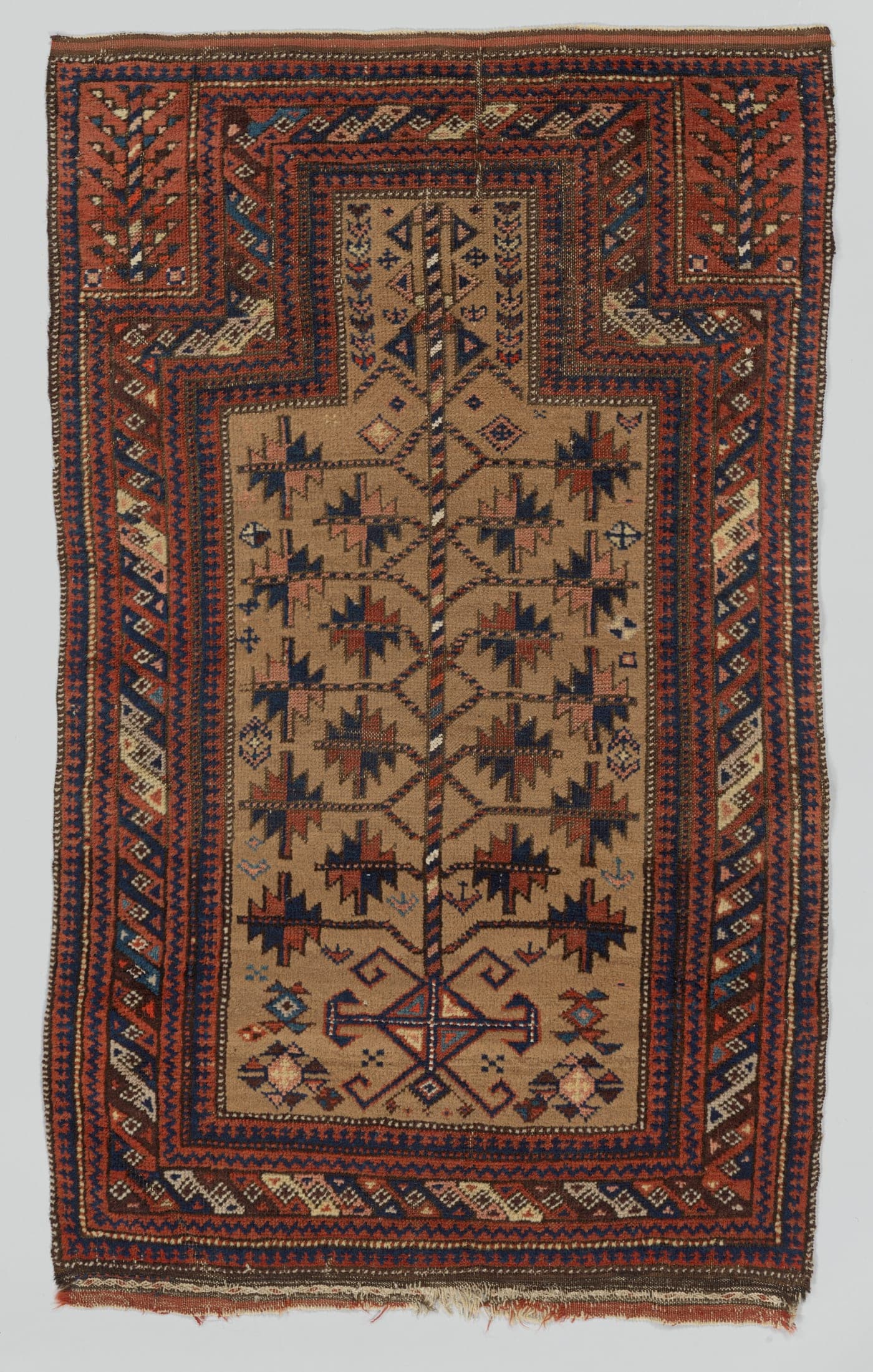 A small dark tribal rug in aubergine, blue-black and camel, with a narrow field of stylised forms and multiple patterned borders.