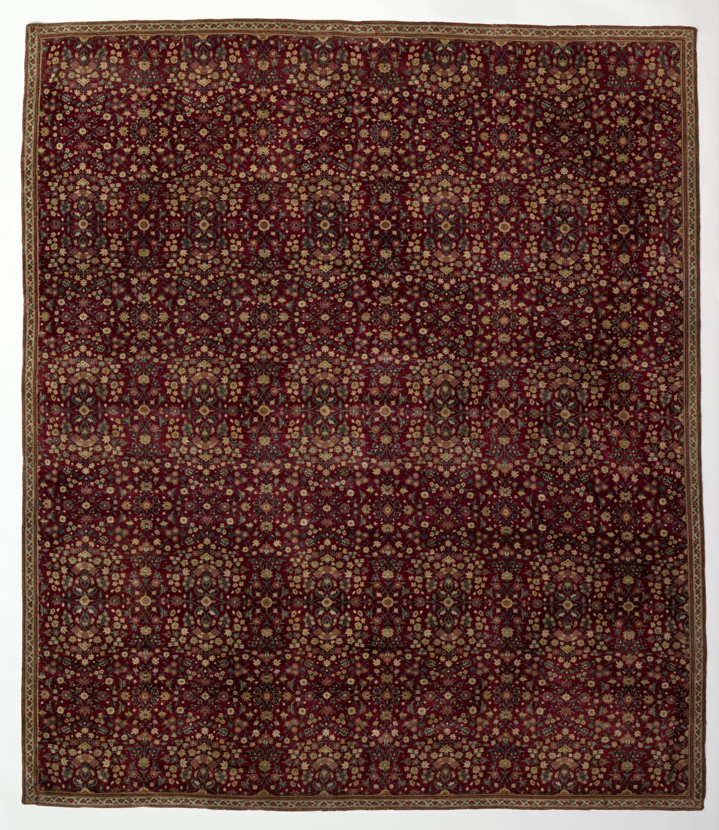 A carpet with a dark ground densely covered in small individually drawn flowering plants, each a distinct species rather than a repeated motif.