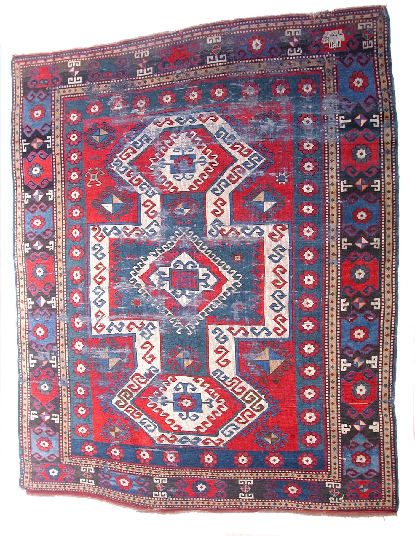 A Caucasian village rug with a strong red field and a bold keyhole medallion in dark blue and ivory, drawn in stepped angular outlines.