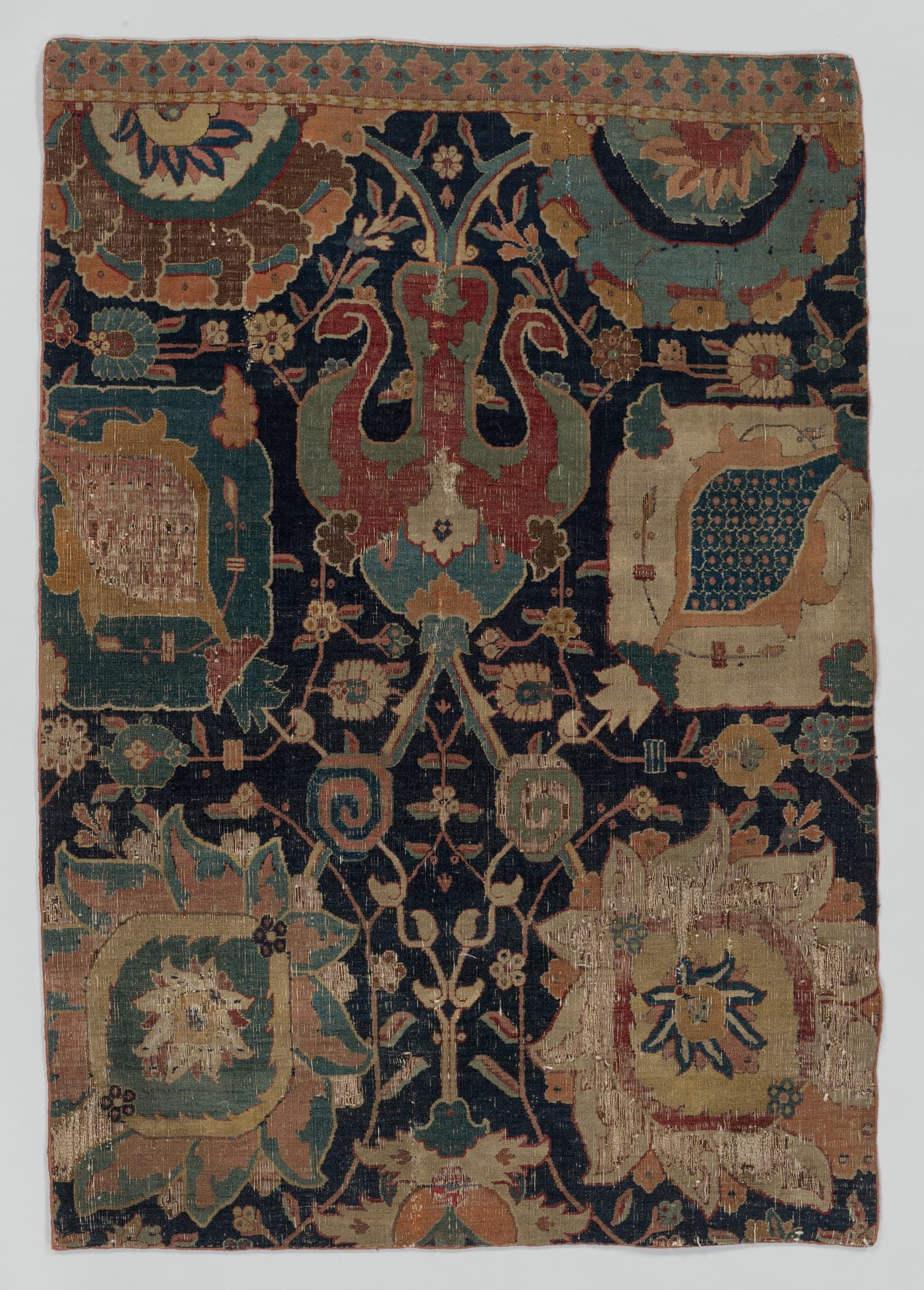 A 17th-century Kerman carpet with a formal field of vases and flowering plants arranged in a lattice, drawn in flowing curves on a dark ground.