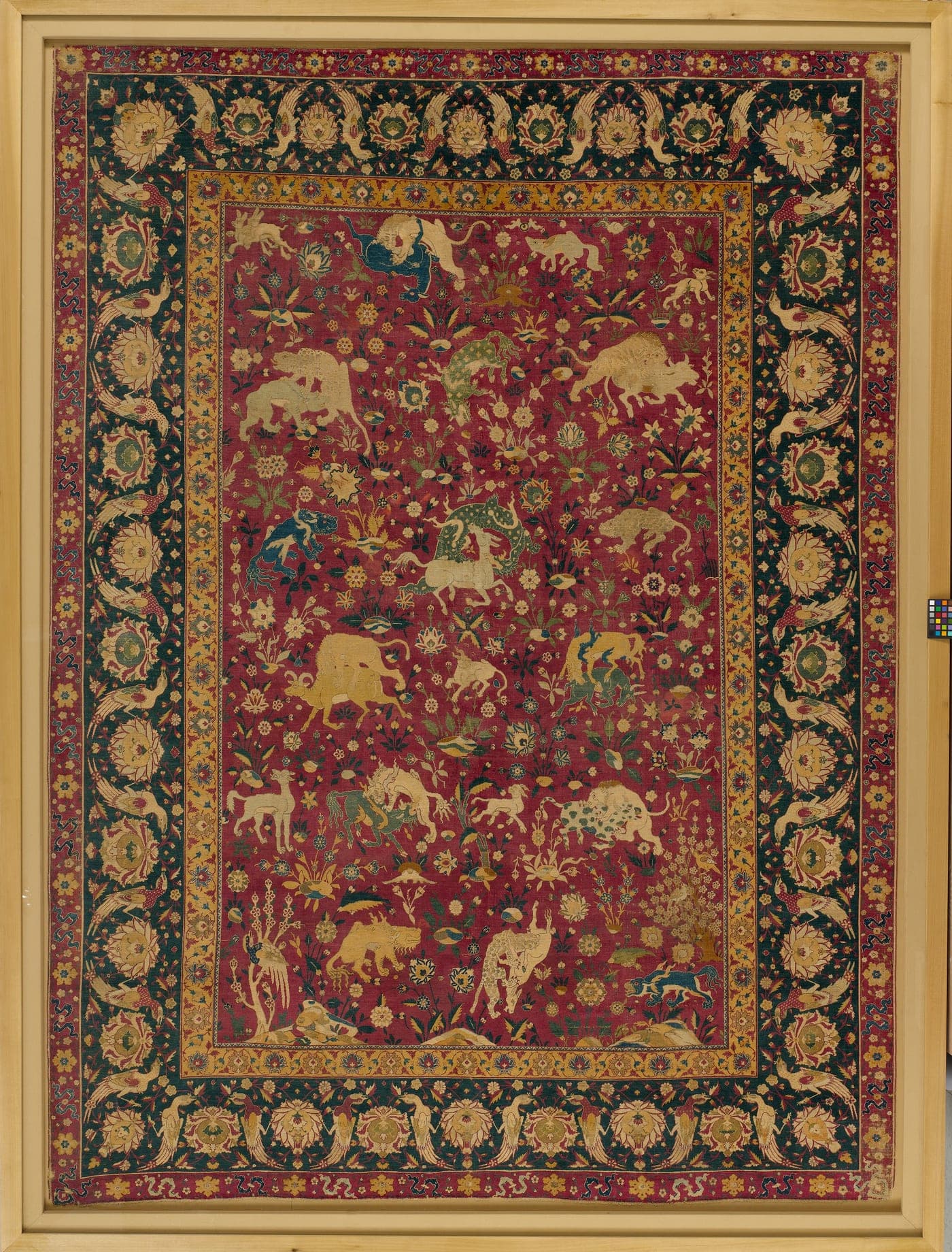 A silk carpet with a red ground, filled with curving vine scrollwork and animals in combat, rendered in flowing curvilinear detail.