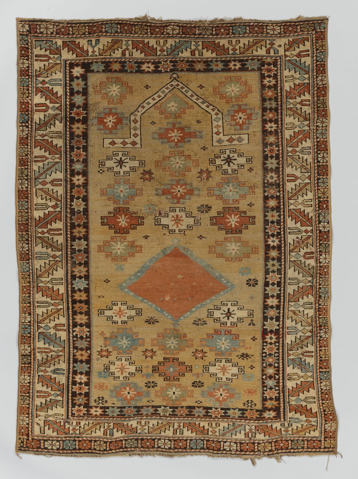 A village rug with a strong geometric field, the blue ground shifting visibly in horizontal bands between two slightly different shades.